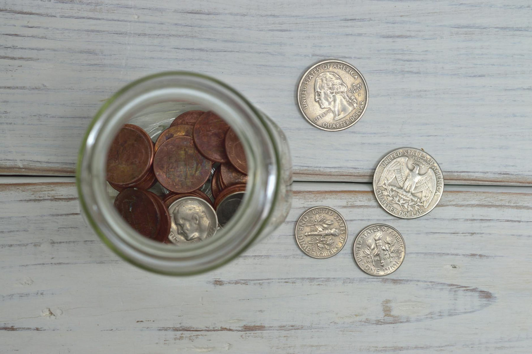 Top view of a jar filled with coins placed on a wooden table, depicting savings. on Earth Wise Budget