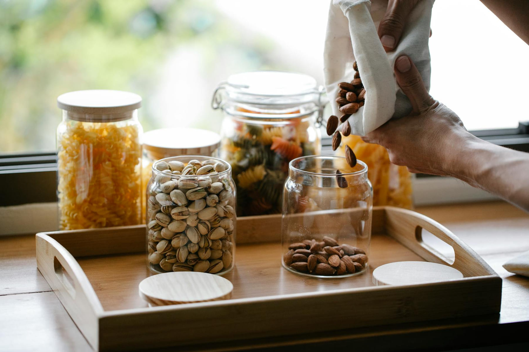 Discover sustainable kitchen storage using reusable bags and glass jars on a wooden tray. on Earth Wise Budget