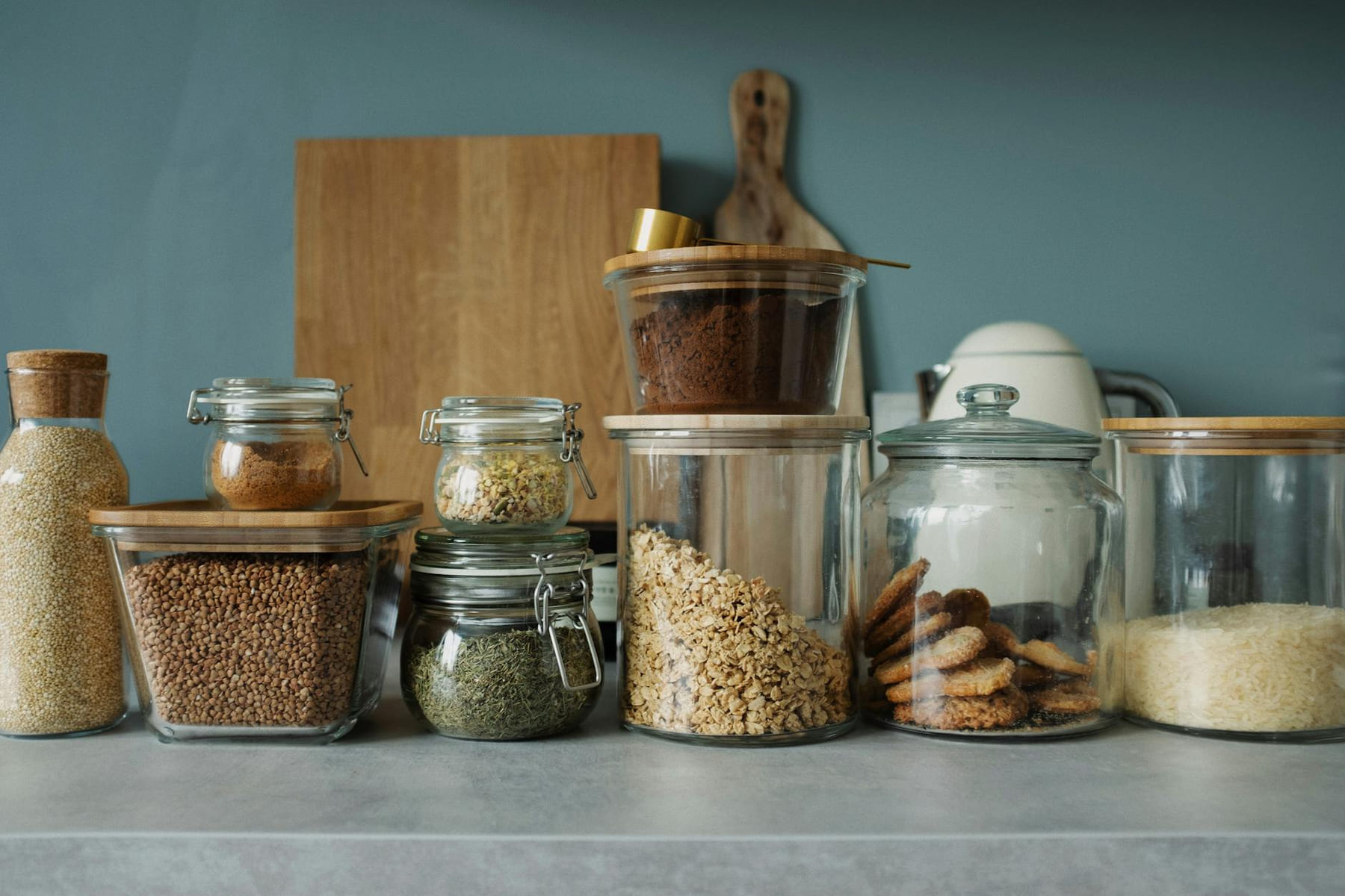 Neatly arranged glass jars with cookies, oats, spices, and ingredients on a kitchen counter. on Earth Wise Budget