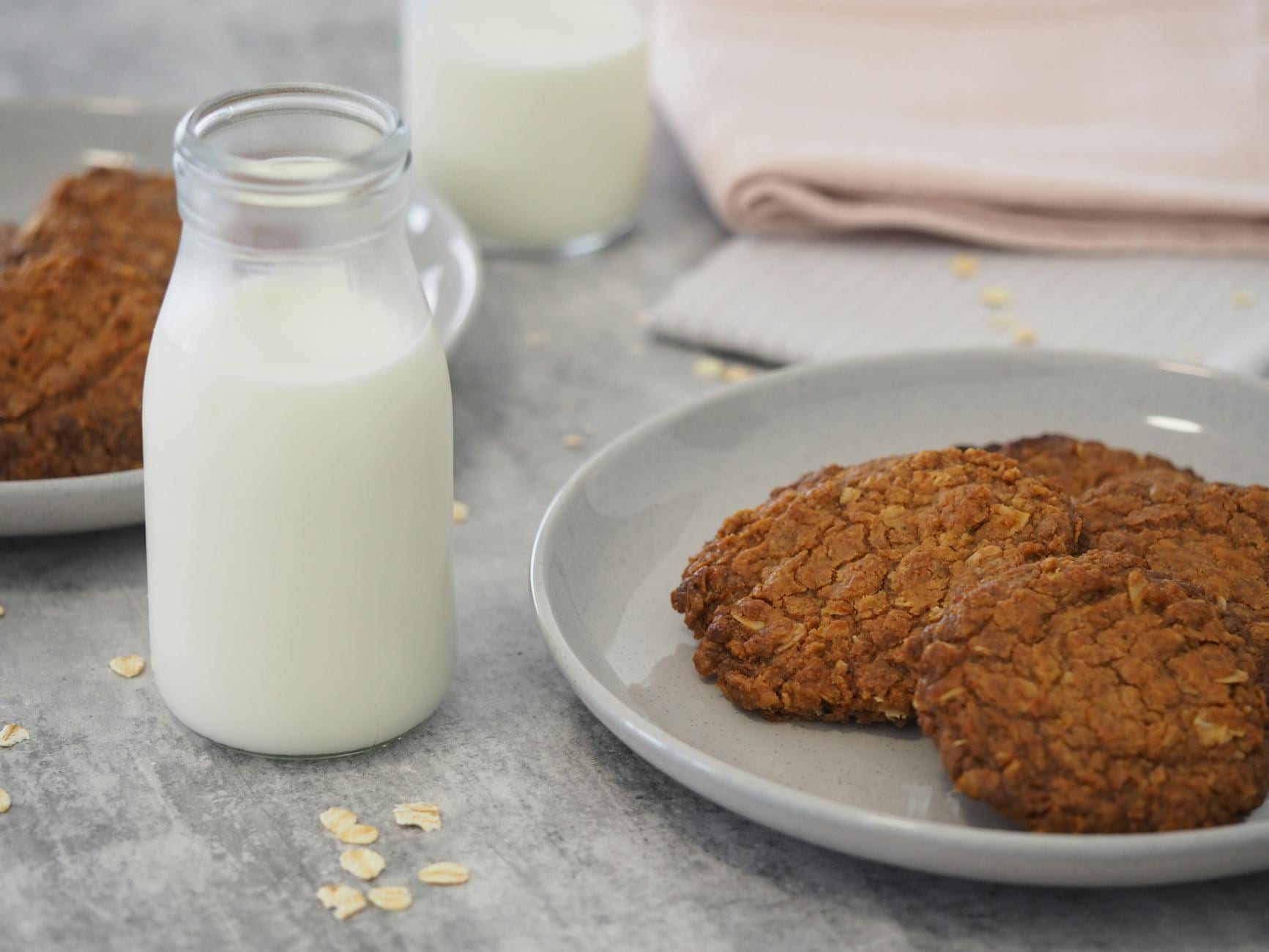 Close-up of oatmeal cookies with milk in glass bottle on a kitchen counter. on Earth Wise Budget