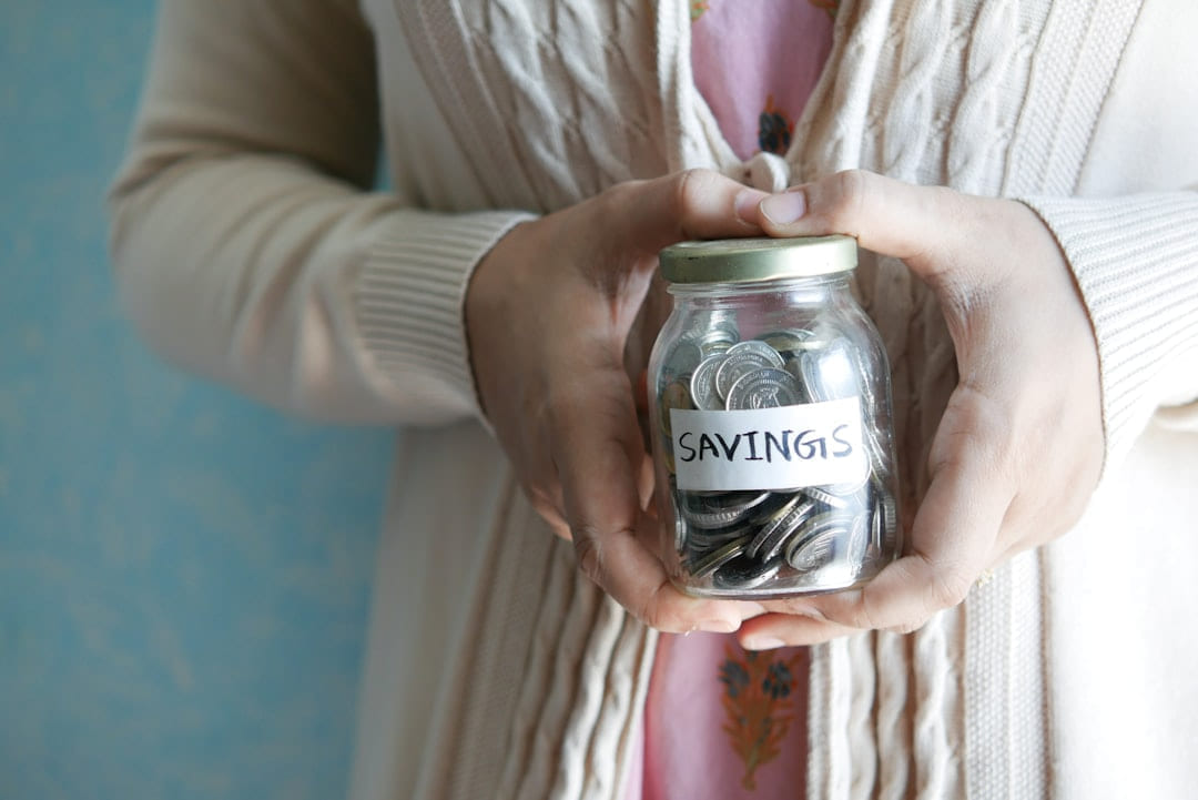 a woman holding a jar with savings written on it on Earth Wise Budget