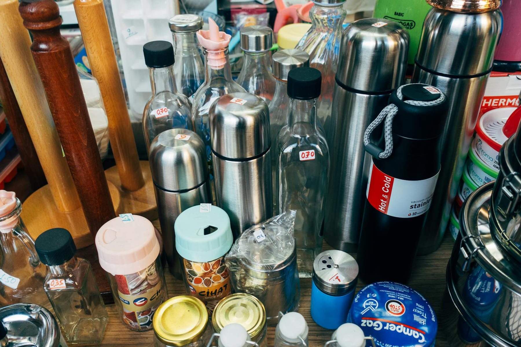 A variety of kitchen containers including bottles, jars, and thermos flasks on display. on Earth Wise Budget